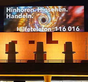 Internationaler Tag gegen Gewalt an Frauen - am Staatstheater Darmstadt projeziert die Lichtinstallation die Hilfetelefonnummer an eine Wand ( Fotogalerie © Peter Henrich / HEN-FOTO )